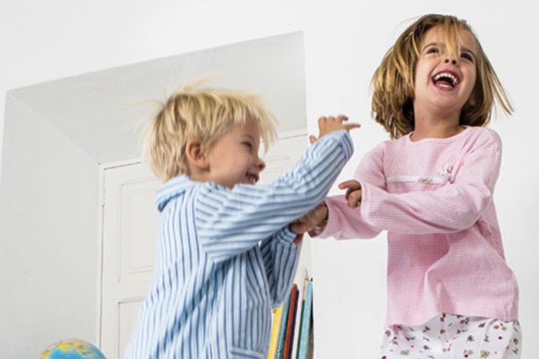 Niño y niña riendo y jugando dentro